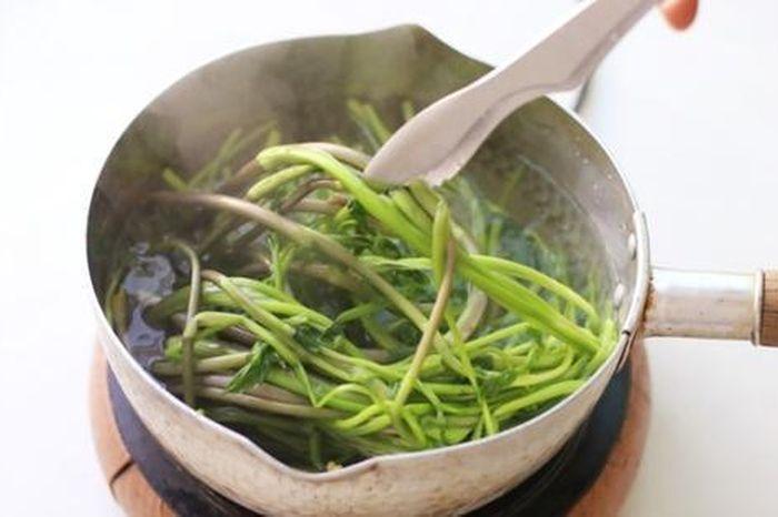 Một người đang rửa rau xà lách dưới vòi nước chảy mạnh